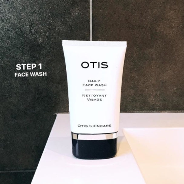 White tube of OTIS Daily Face Wash against charcoal gray tiles