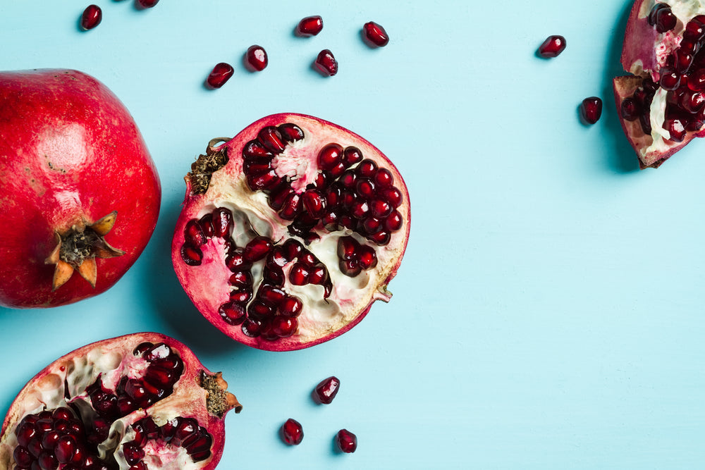 Can Antioxidants Make You Look Younger? What The Science Says. Image of antioxidant pomegranate cut open on turquoise background