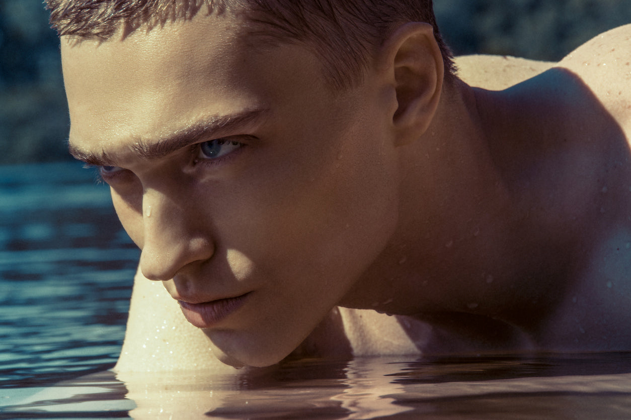 Handsome male model with oily skin in clear blue water