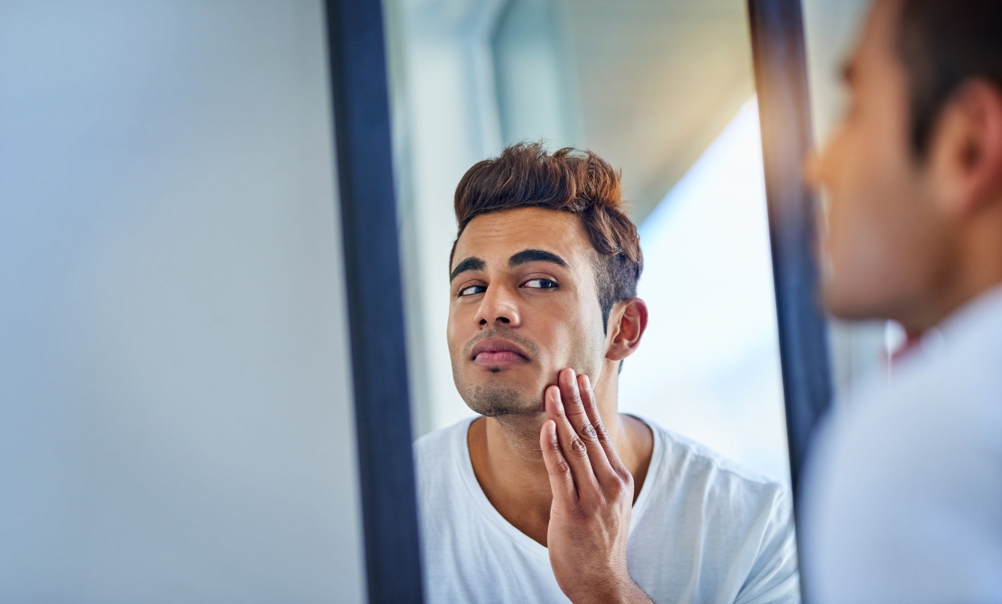 Handsome young man looking into mirror