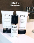 OTIS Hydrating Daily Moisturizer with other OTIS products against charcoal gray tiles