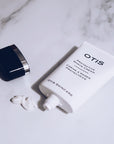 Tube of OTIS Protective Shave Cream open on marble surface with cream squeezed out  and lid off